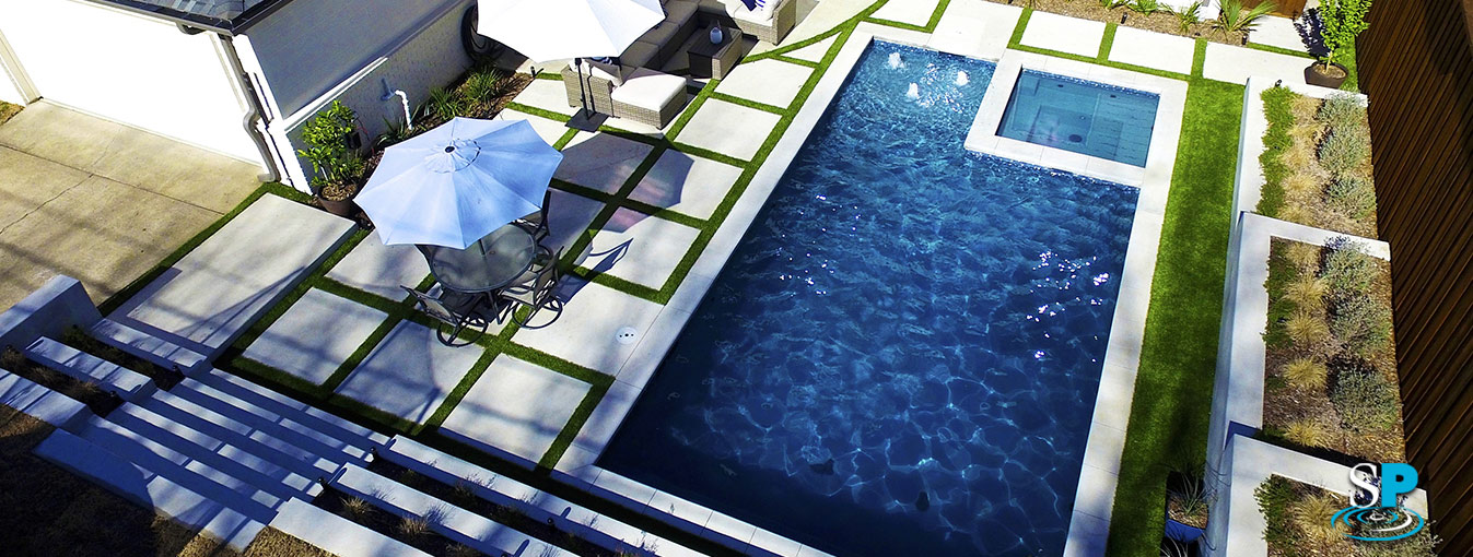 a drone image of a pool and spa, a tavertine decking